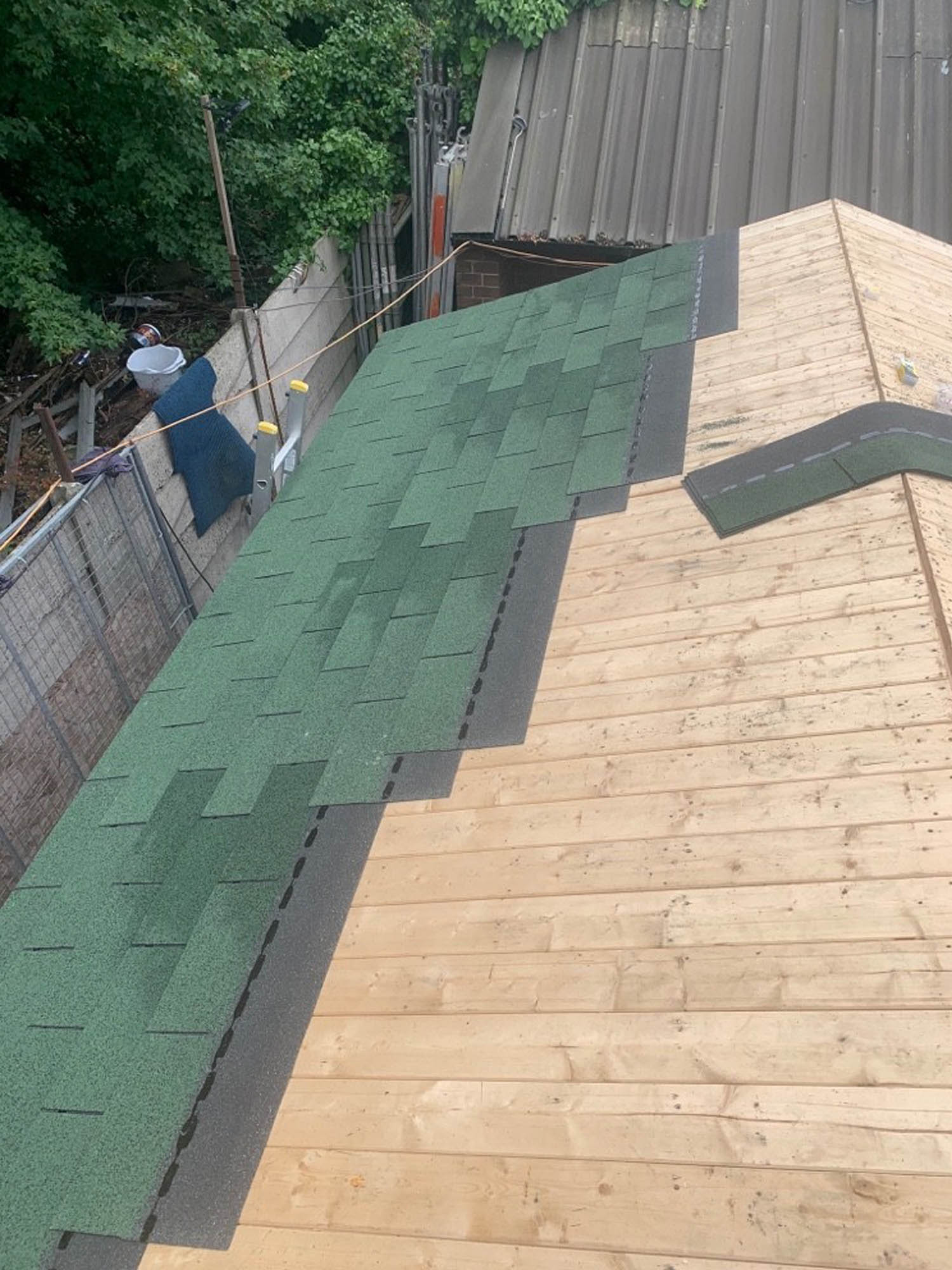 Installation of green asphalt shingles on a wooden roof deck